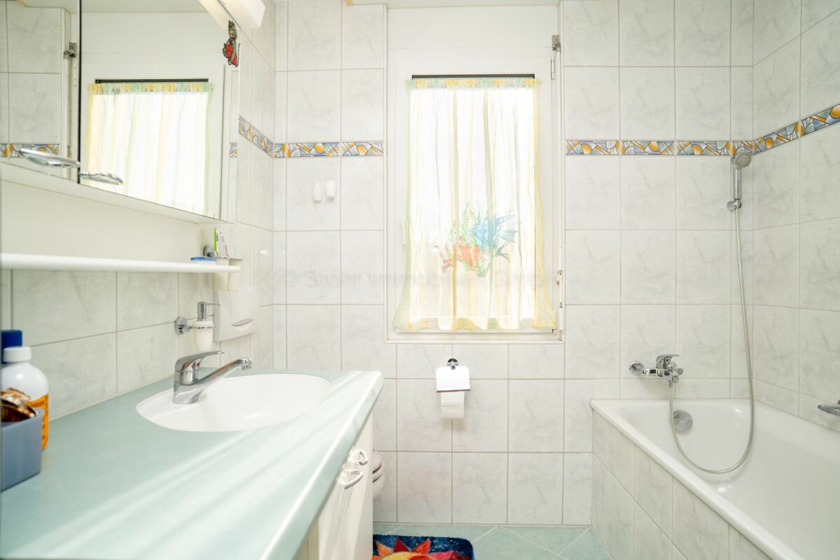 Helles Badezimmer mit Badewanne und Waschplatz