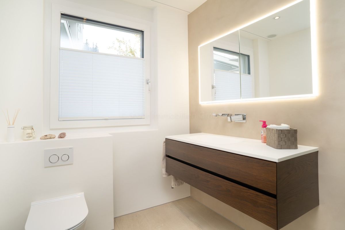 Modernes Badezimmer mit beleuchtetem Spiegel und Waschtisch