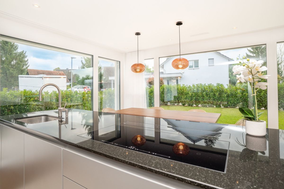 Offene Küche mit großflächigen Fenstern und Gartenblick