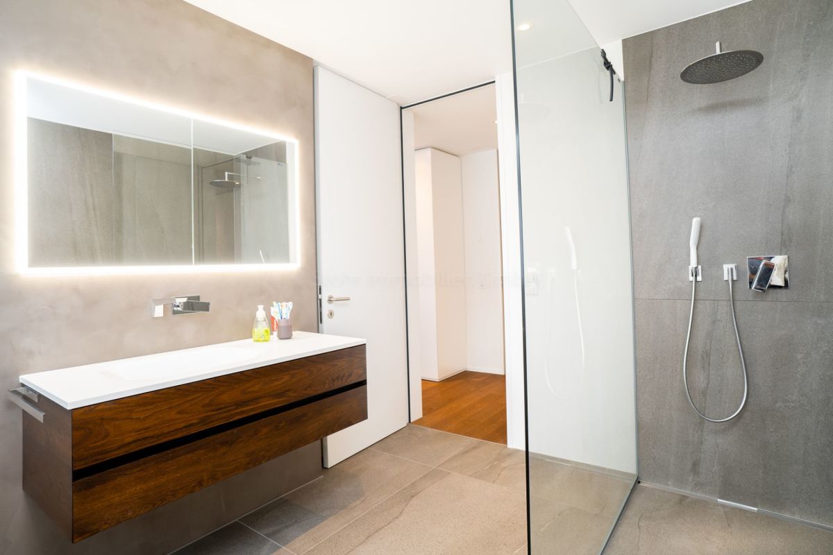 Modernes Badezimmer mit Walk-in-Dusche und beleuchtetem Spiegel