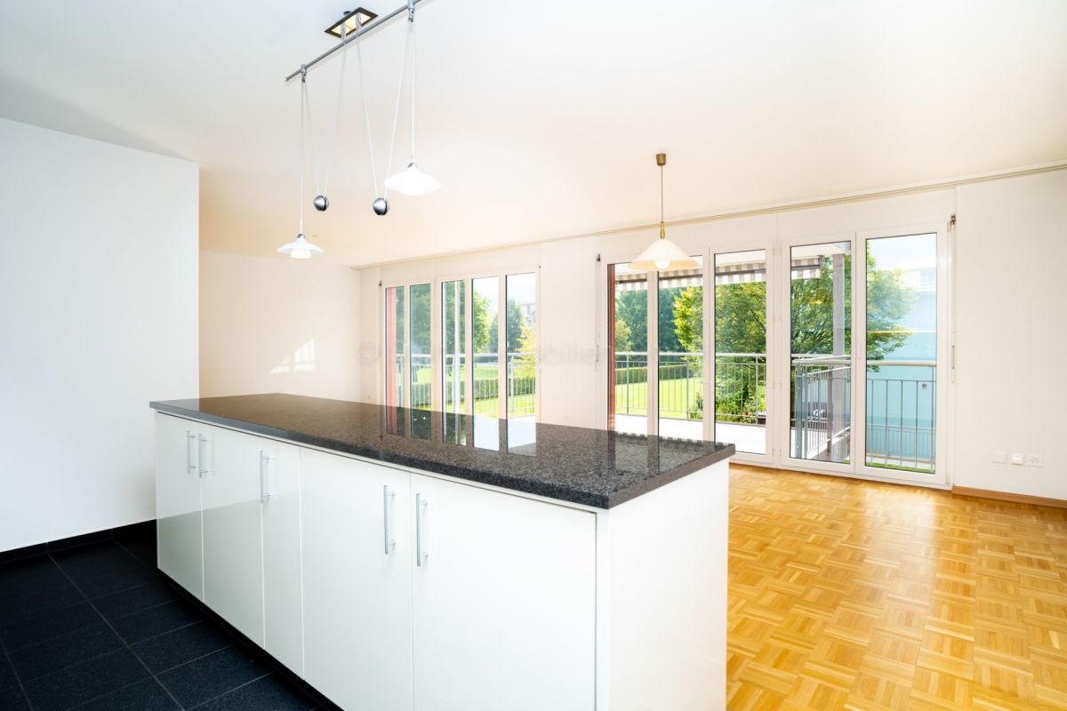 Offener Wohnbereich mit Kücheninsel und Balkonblick