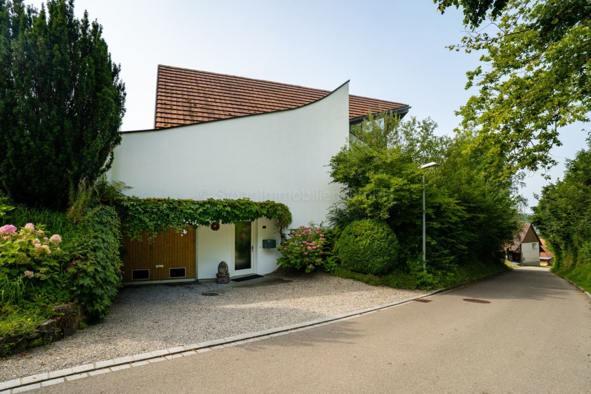 Außenansicht eines modernen Wohnhauses mit geneigtem Dach und grüner Umgebung