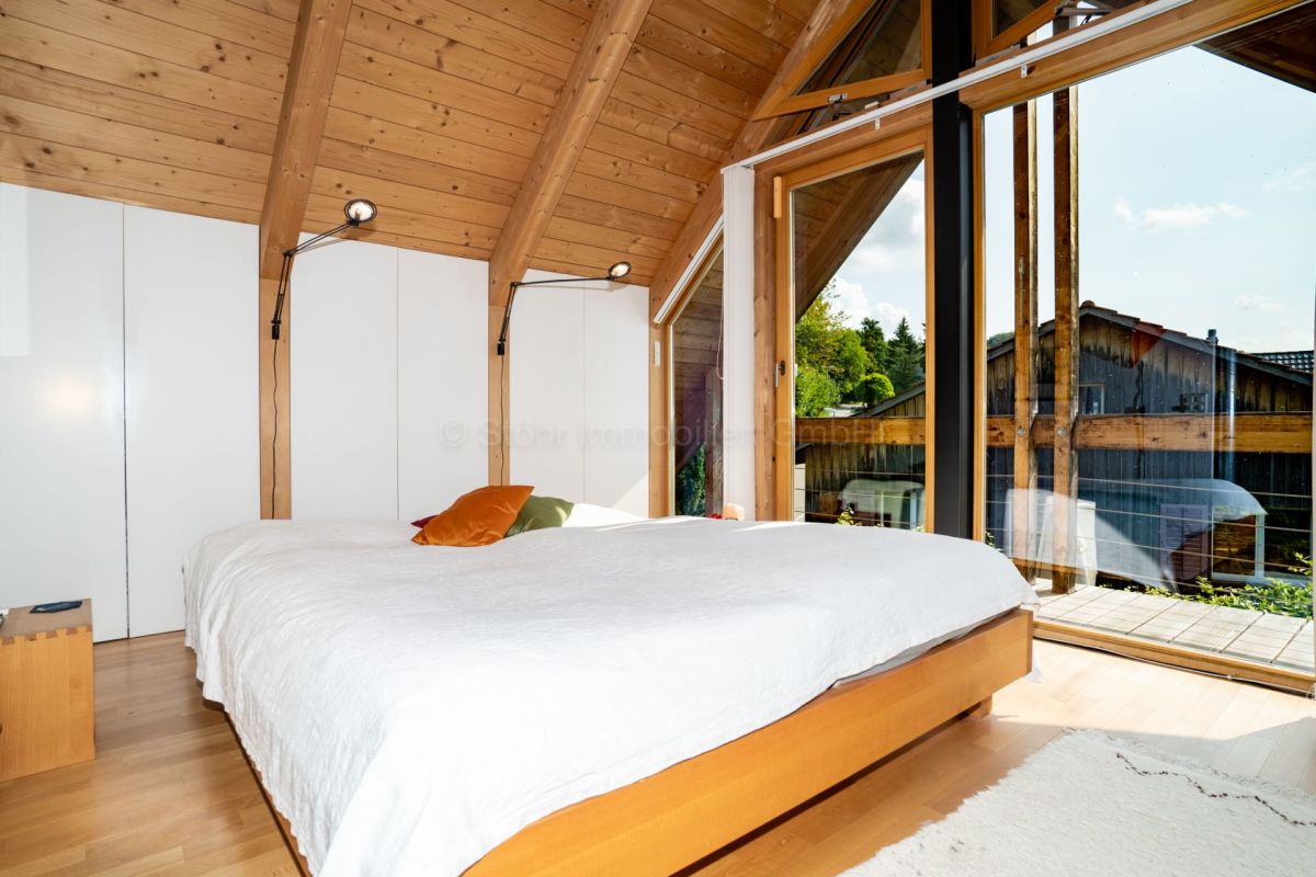 Helles Schlafzimmer mit Holzdecke und Balkonblick