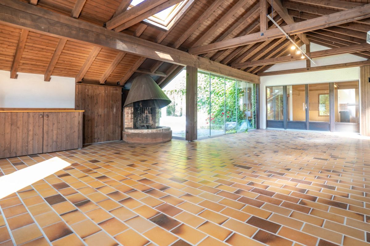 Großer rustikaler Innenraum mit Kamin und Holzbalkendecke