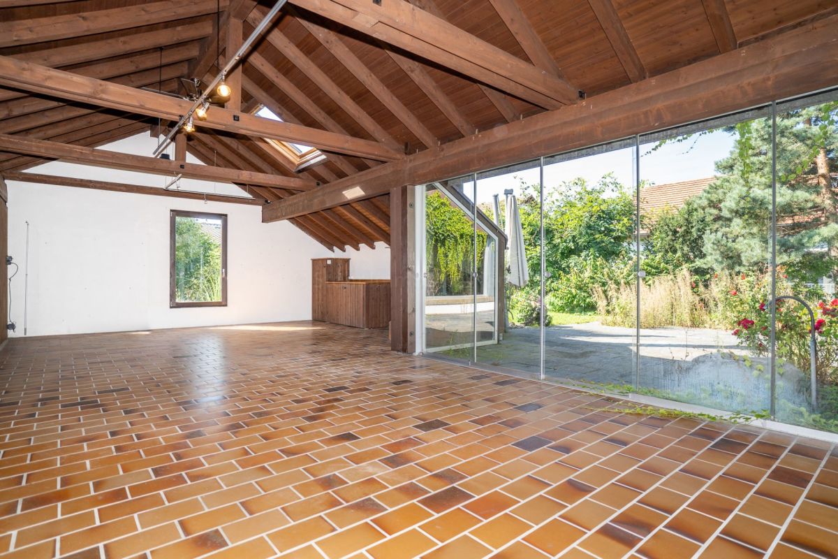Großer Raum mit Holzsparren und Glasfront zum Garten