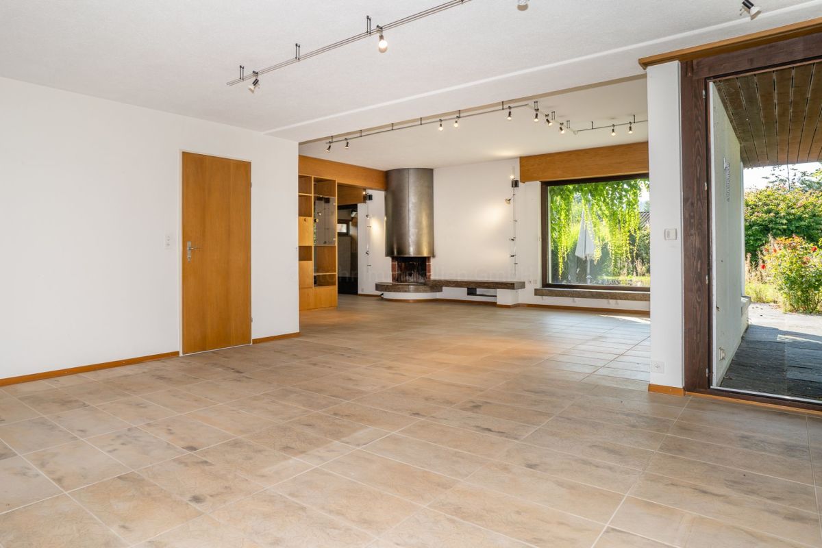 Großer offener Wohnraum mit Kamin und Terrassenzugang
