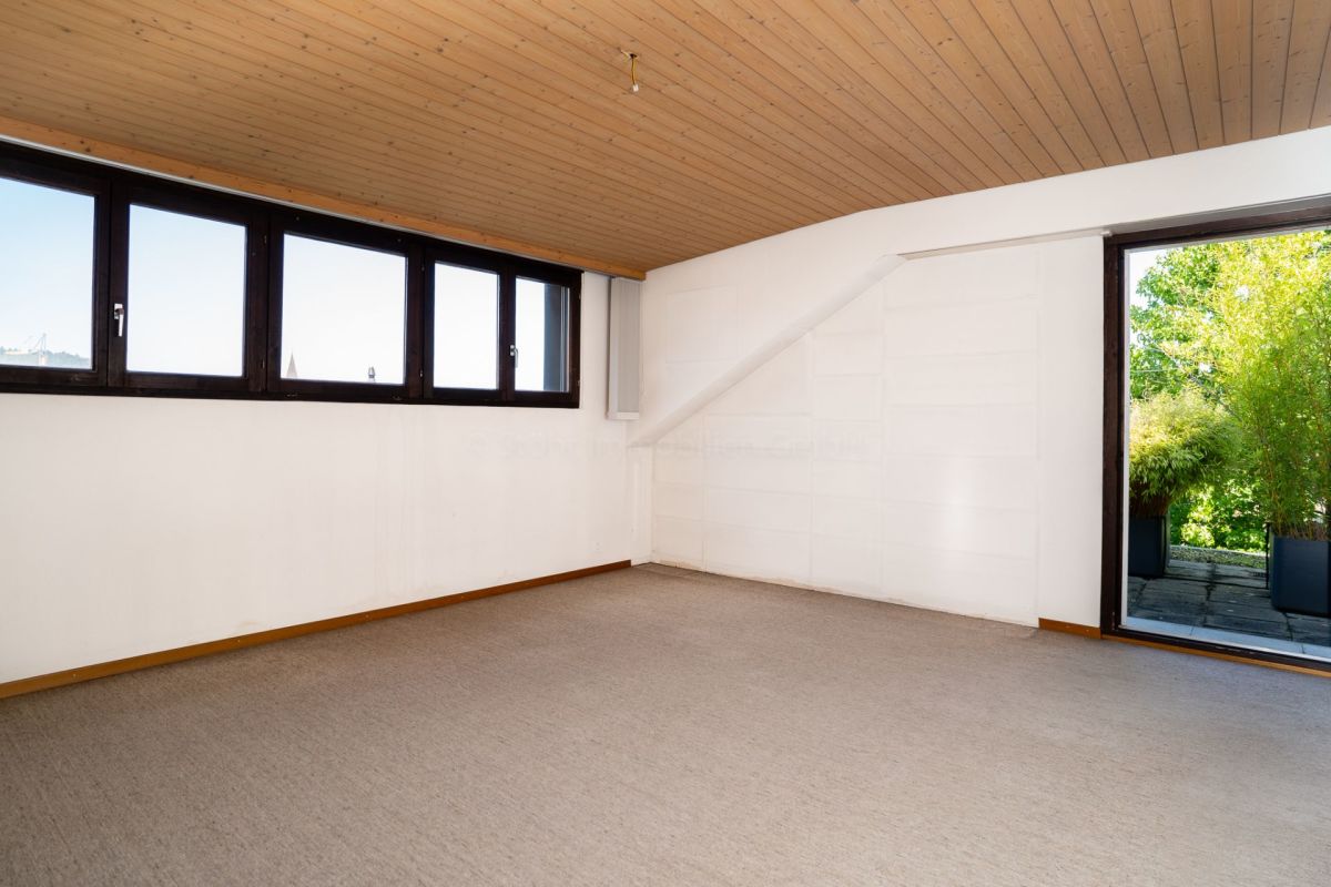 Helles Zimmer mit Holzdecke und großen Fenstern