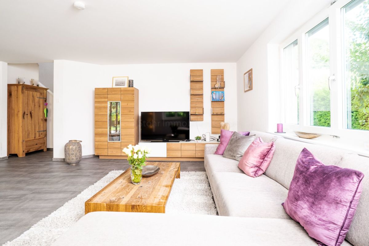 Heller Wohnbereich mit großer Fensterfront und Holzmöbeln