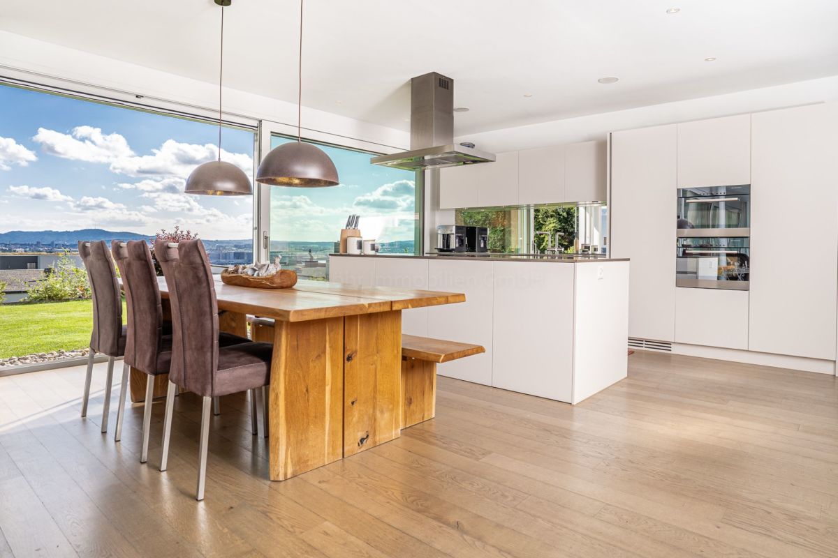 Offene Wohnküche mit Panoramafenster und Holztisch
