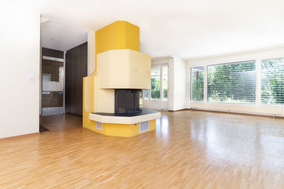 Großer Wohnraum mit Kamin und Blick ins Grüne