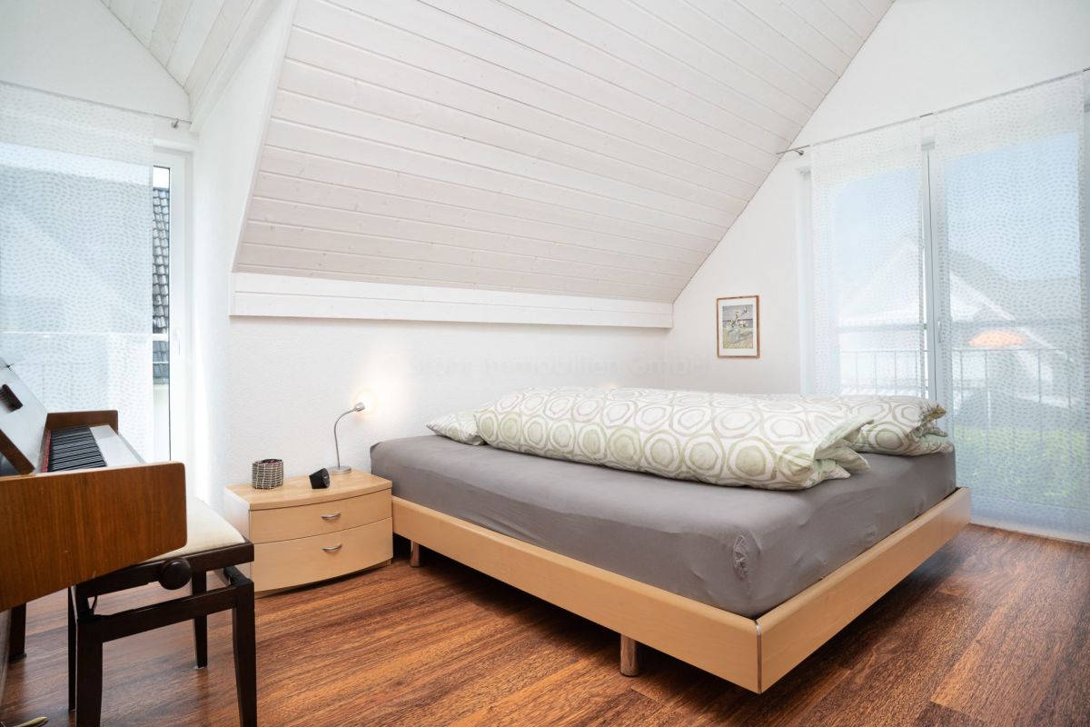 Dachgeschoss-Schlafzimmer mit Bett und hoher Decke