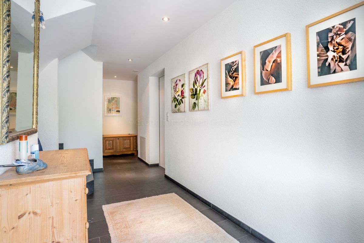 Heller Eingangsflur mit Kunst und Holzmöbel