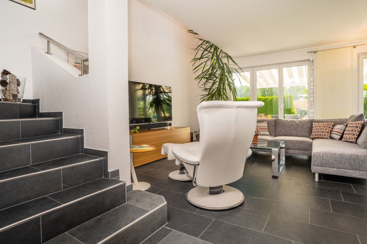 Wohnzimmer mit Treppe und großen Fensterfronten