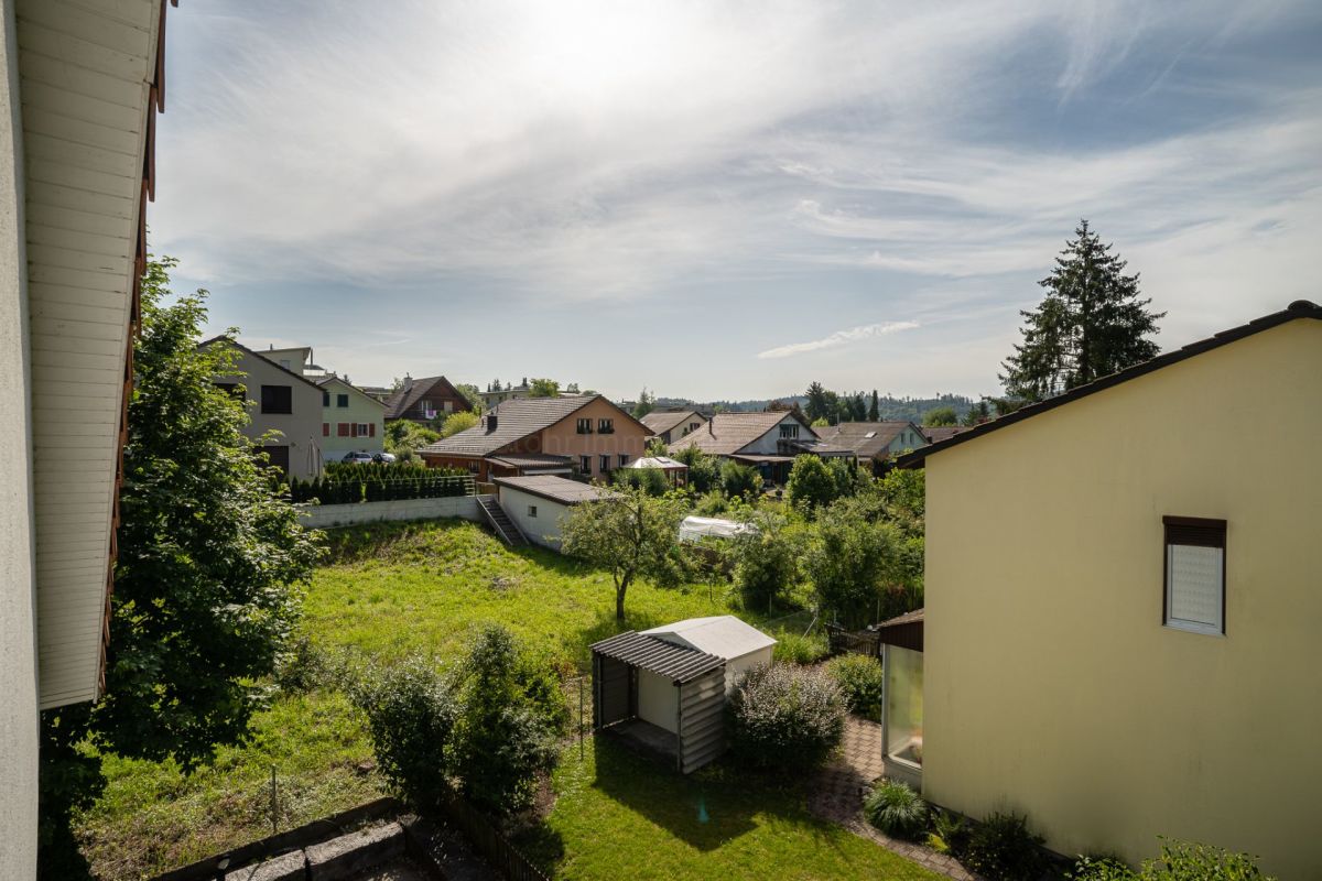 Blick in einen grünen Garten mit umliegenden Wohnhäusern