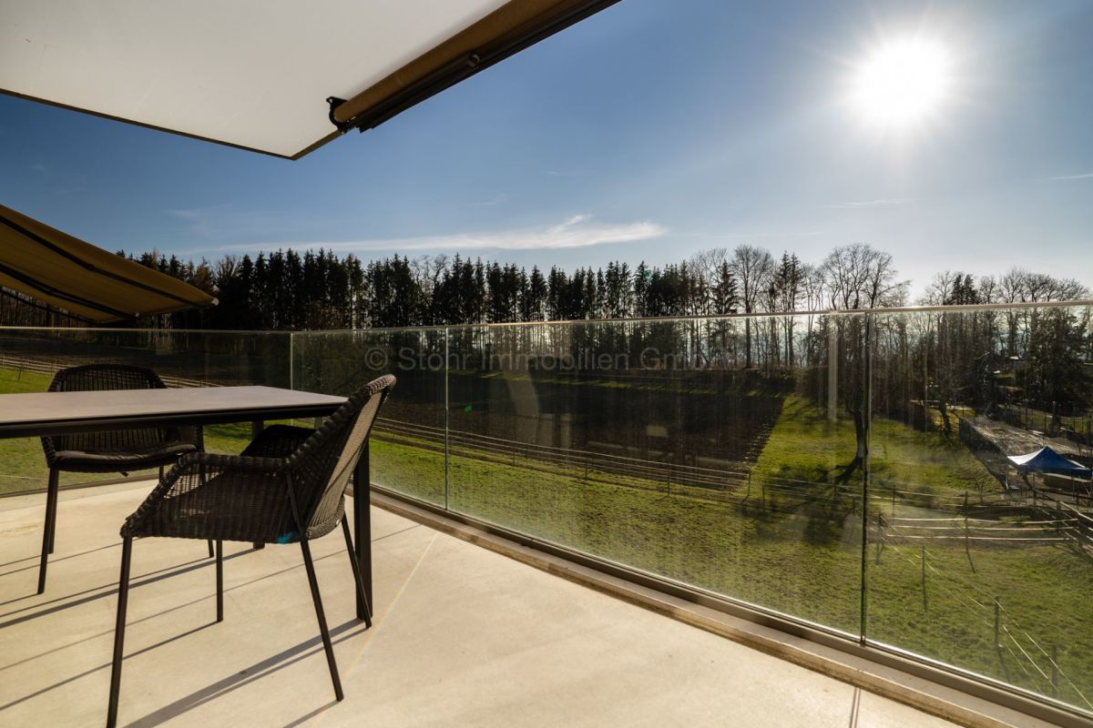 Balkon mit Glasgeländer und weitem Grünblick