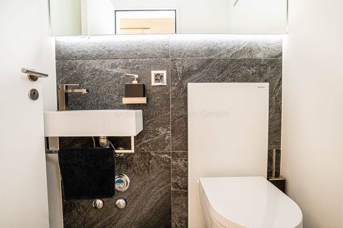 Modernes Gäste-WC mit Natursteinwand und wandhängendem WC
