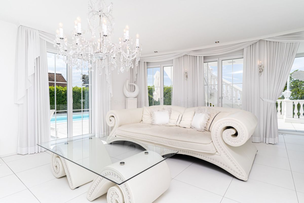 Elegantes, helles Wohnsalon-Interieur mit Kristalllüster und Poolblick