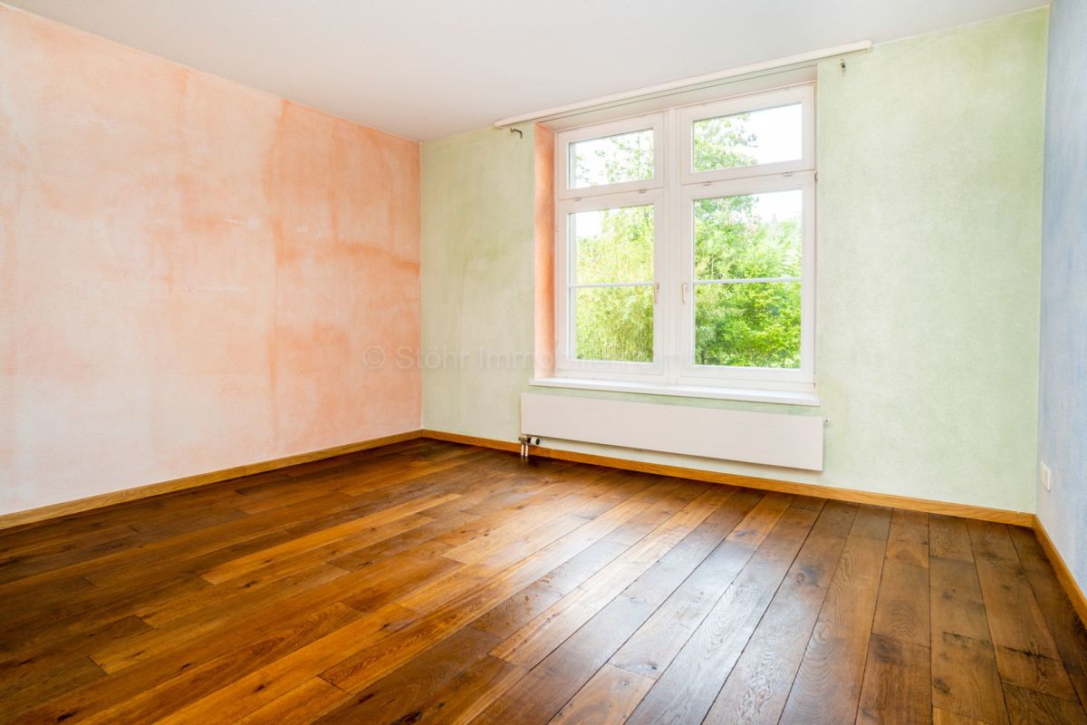 Leerer Wohnraum mit Holzfußboden und großem Fenster