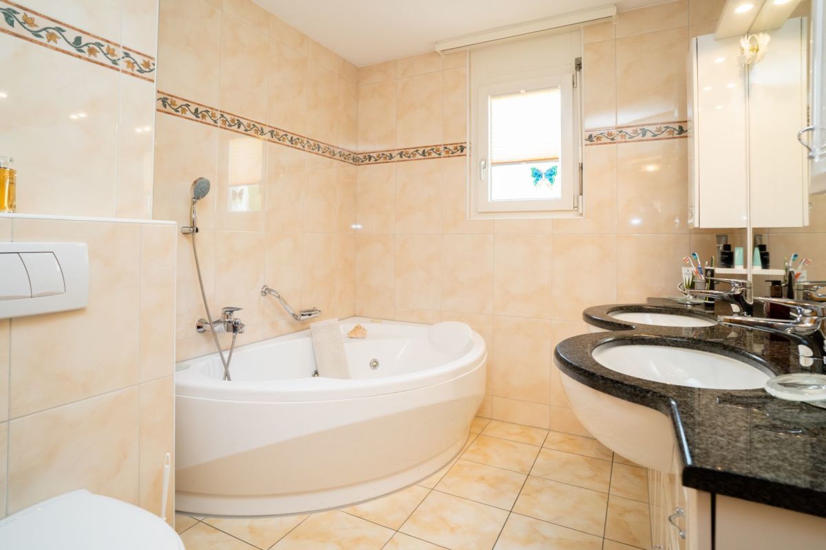 Helles Badezimmer mit Eckbadewanne und Doppelwaschbecken