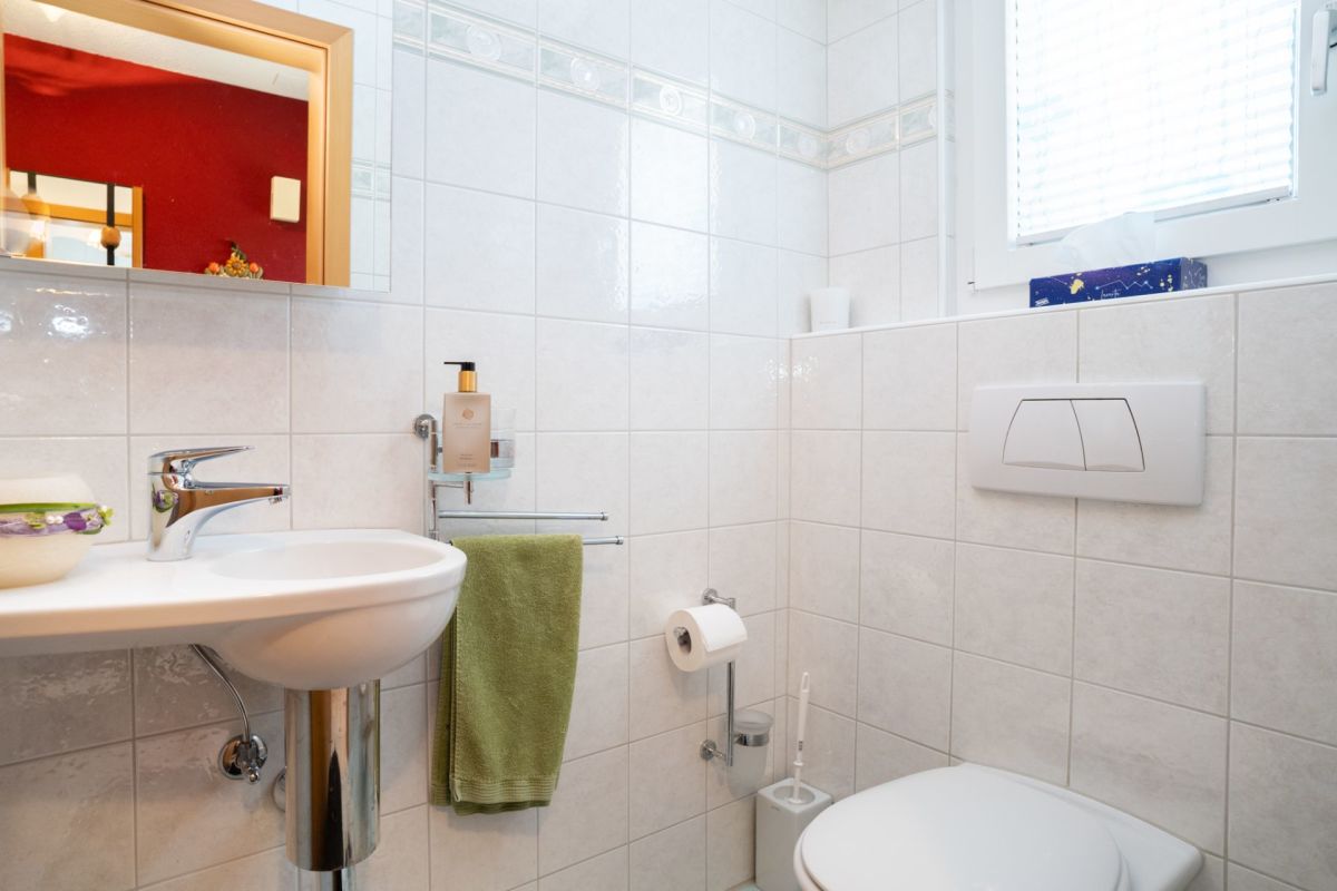 Gäste-WC mit weißer Keramik und großen Wandfliesen