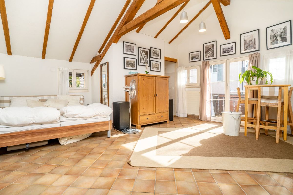 Dachgeschosszimmer mit Schlafbereich und Balkon