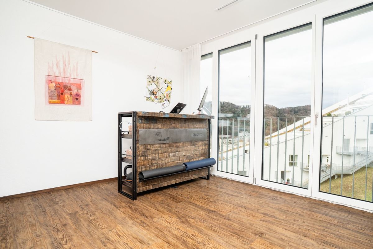 Lichtes Zimmer mit großer Glasfront und Holzoptikboden