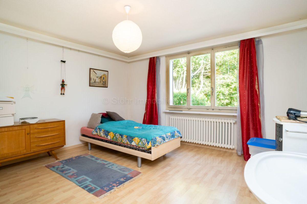 Helles Schlafzimmer mit Einzelbett und Fensterfront
