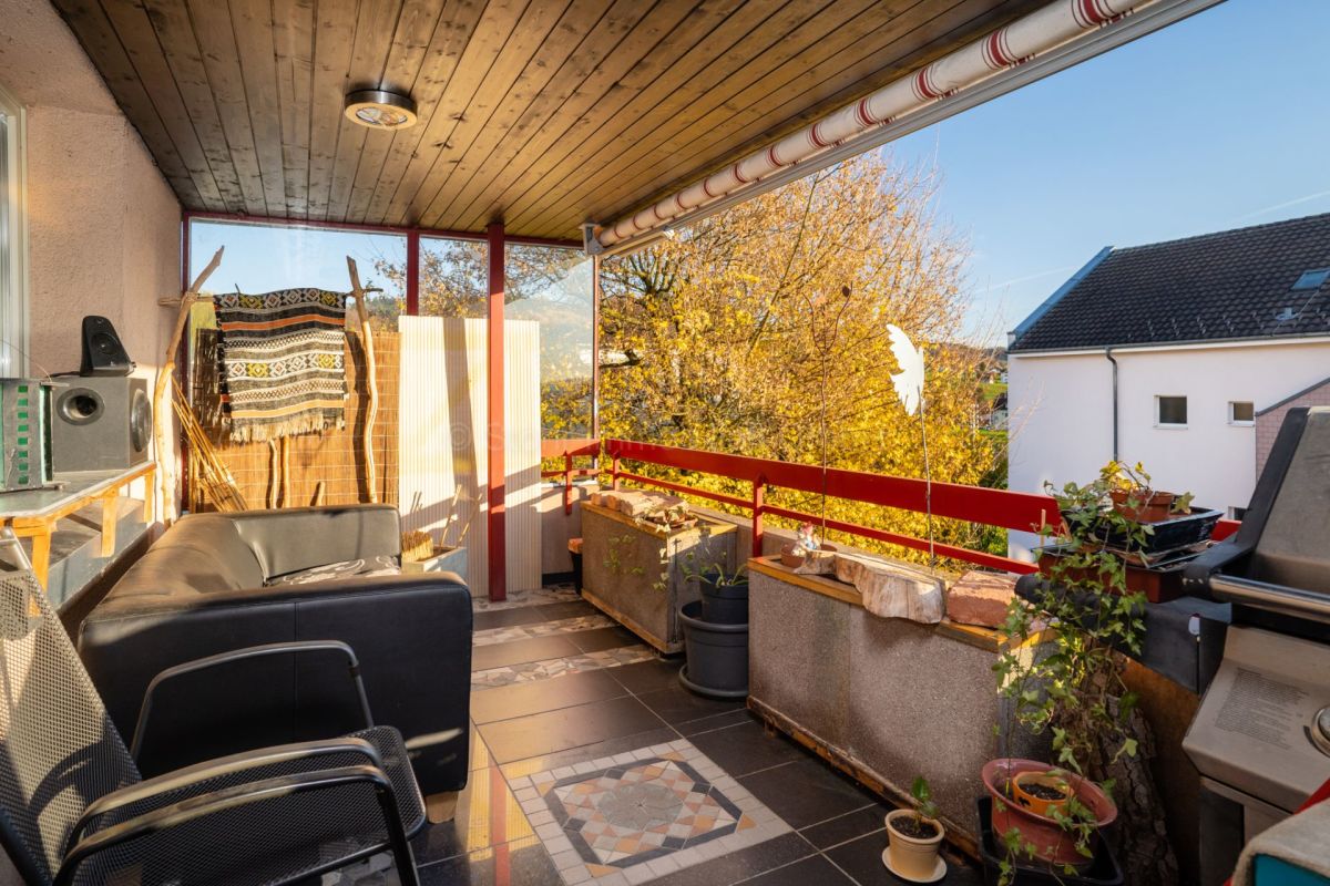 Überdachter Balkon mit Pflanzen und Sitzbereich