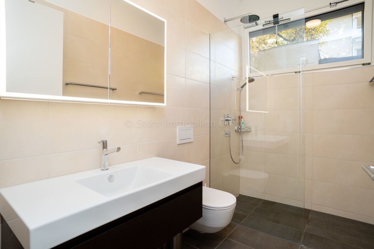 Modernes Badezimmer mit Walk-in-Dusche und beleuchtetem Spiegelspiegelschrank