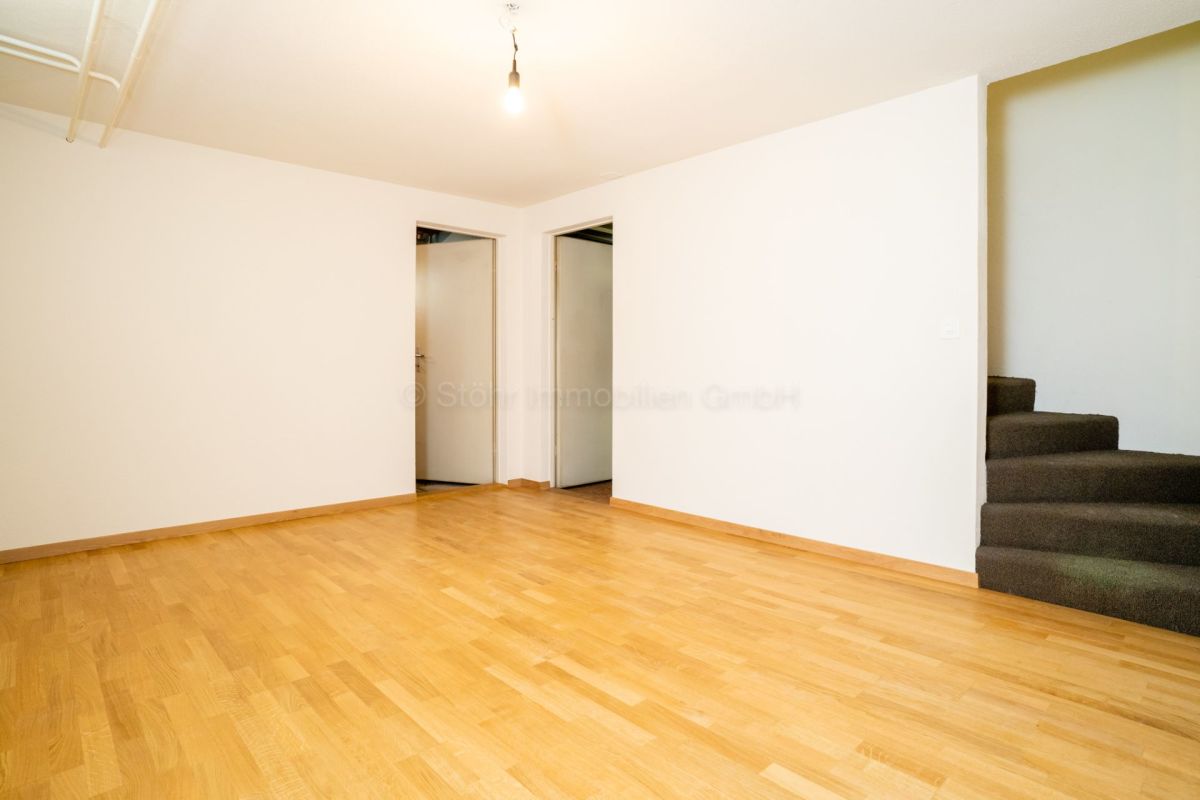 Leerer Wohnraum mit Holzfußboden und Treppe