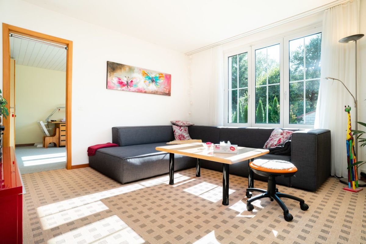 Helles Wohnzimmer mit Ecksofa am Fenster