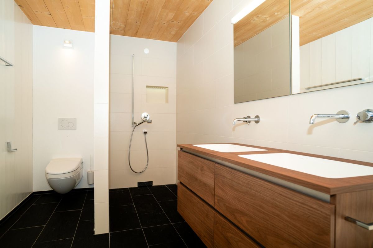 Modernes Badezimmer mit Holzdecke und schwarzem Boden