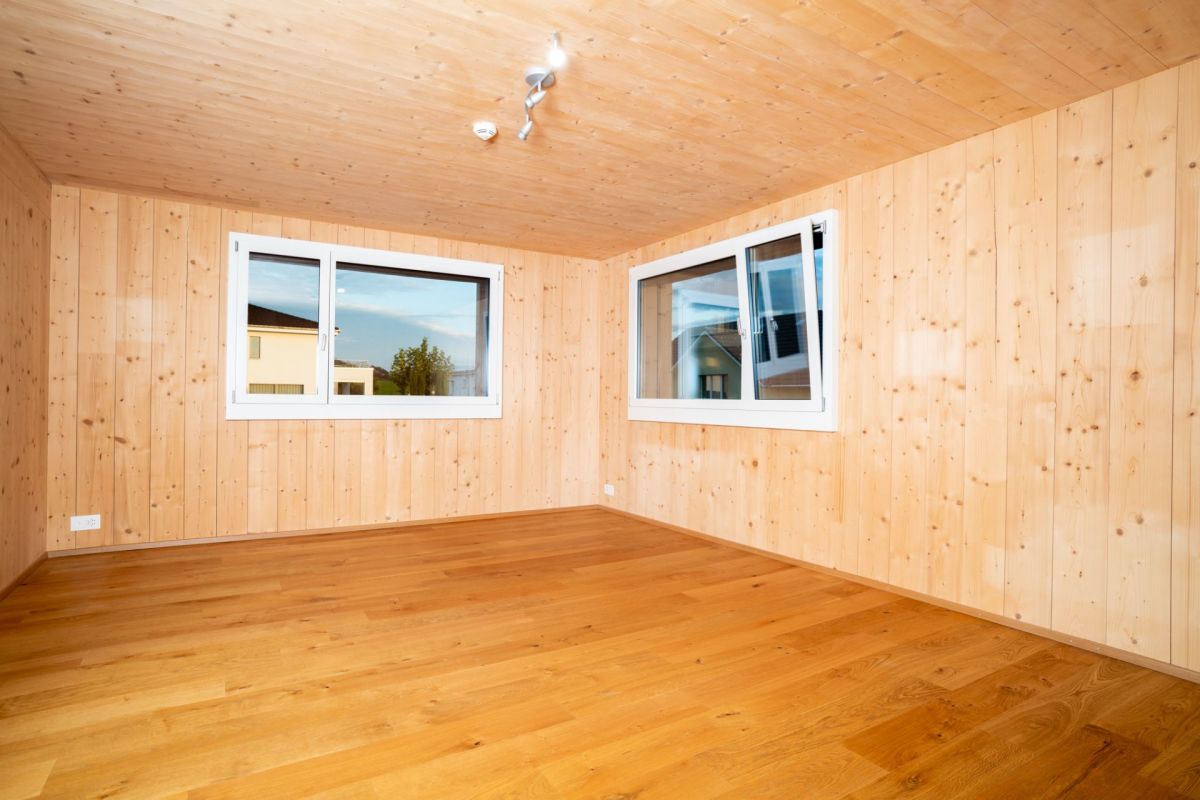 Heller leerer Raum mit Holzverkleidung und zwei Fenstern