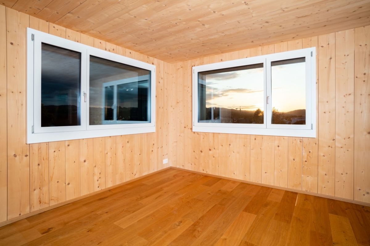 Holzvertäfelter, leerer Raum mit zwei Fenstern