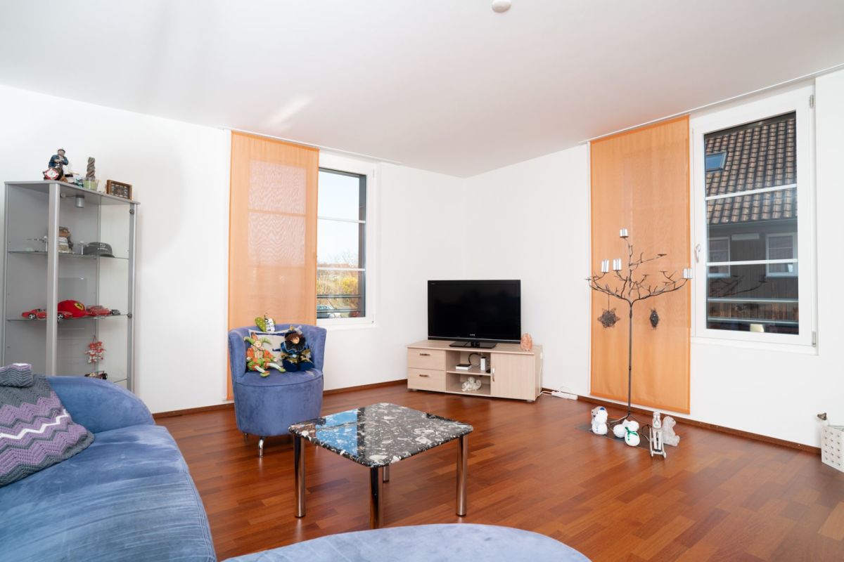 Helles Wohnzimmer mit zwei Fenstern und orangefarbenen Vorhängen