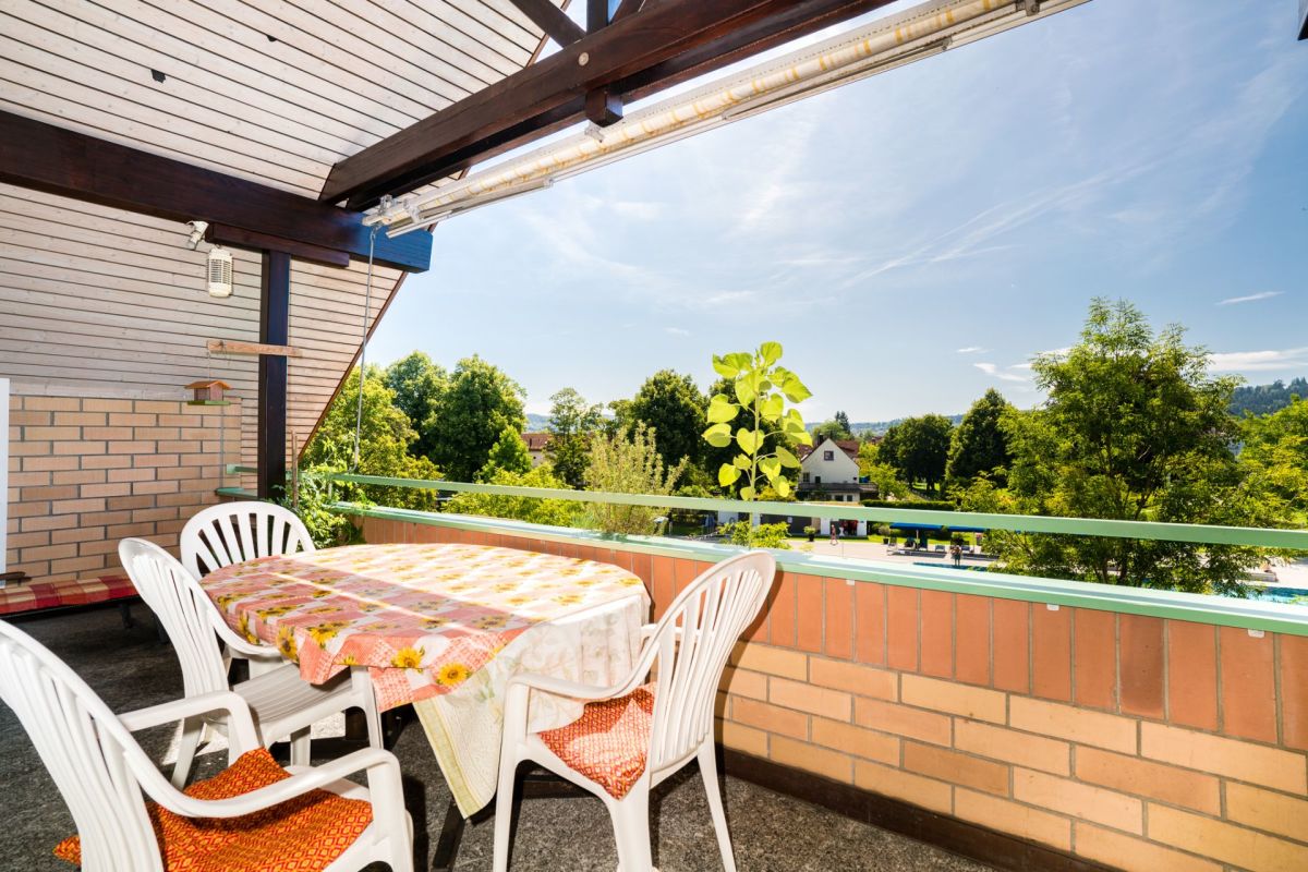 Überdachter Balkon mit Sitzgruppe und Grünblick