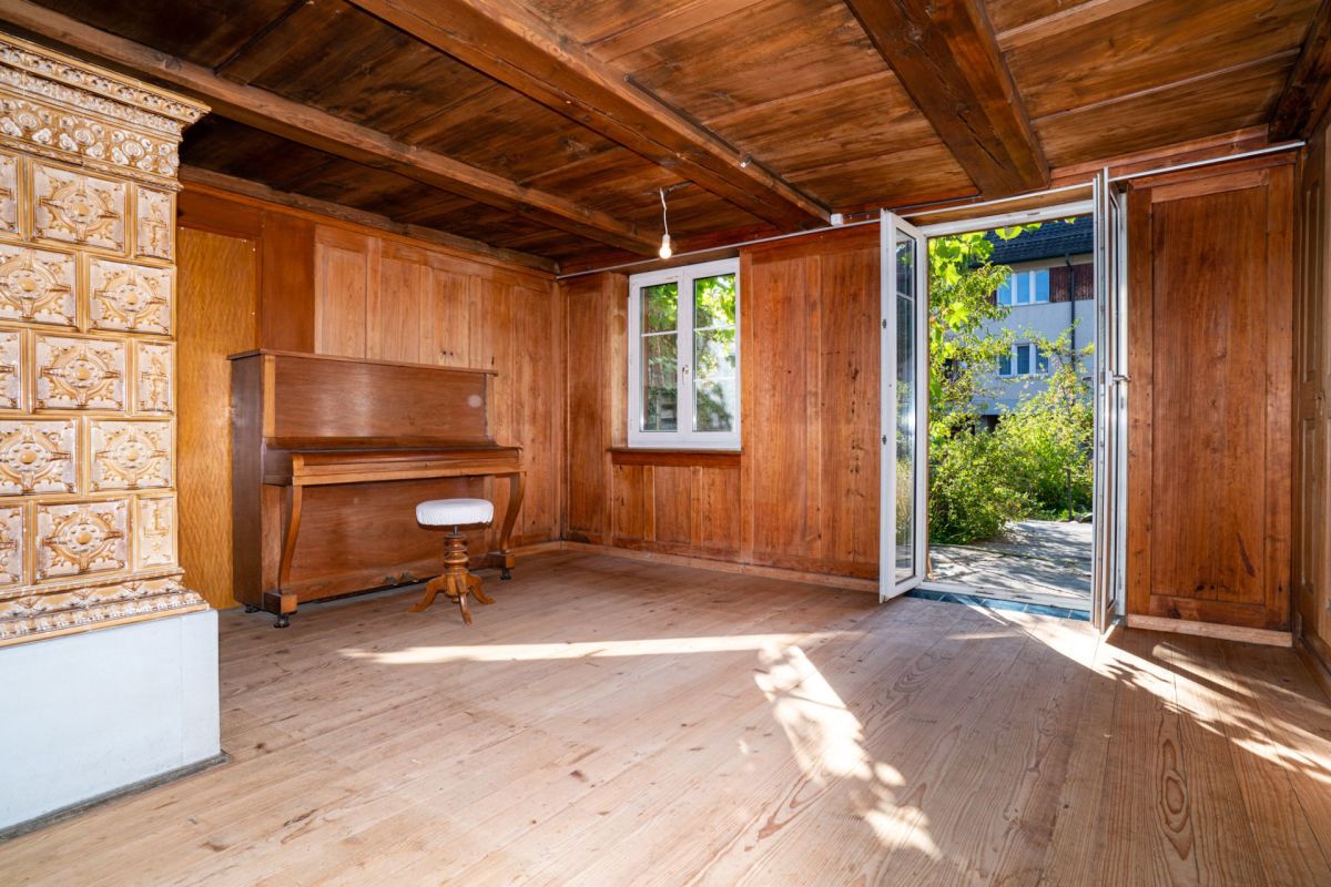 Holzverkleideter Raum mit Klavier und geöffneter Tür zum Garten
