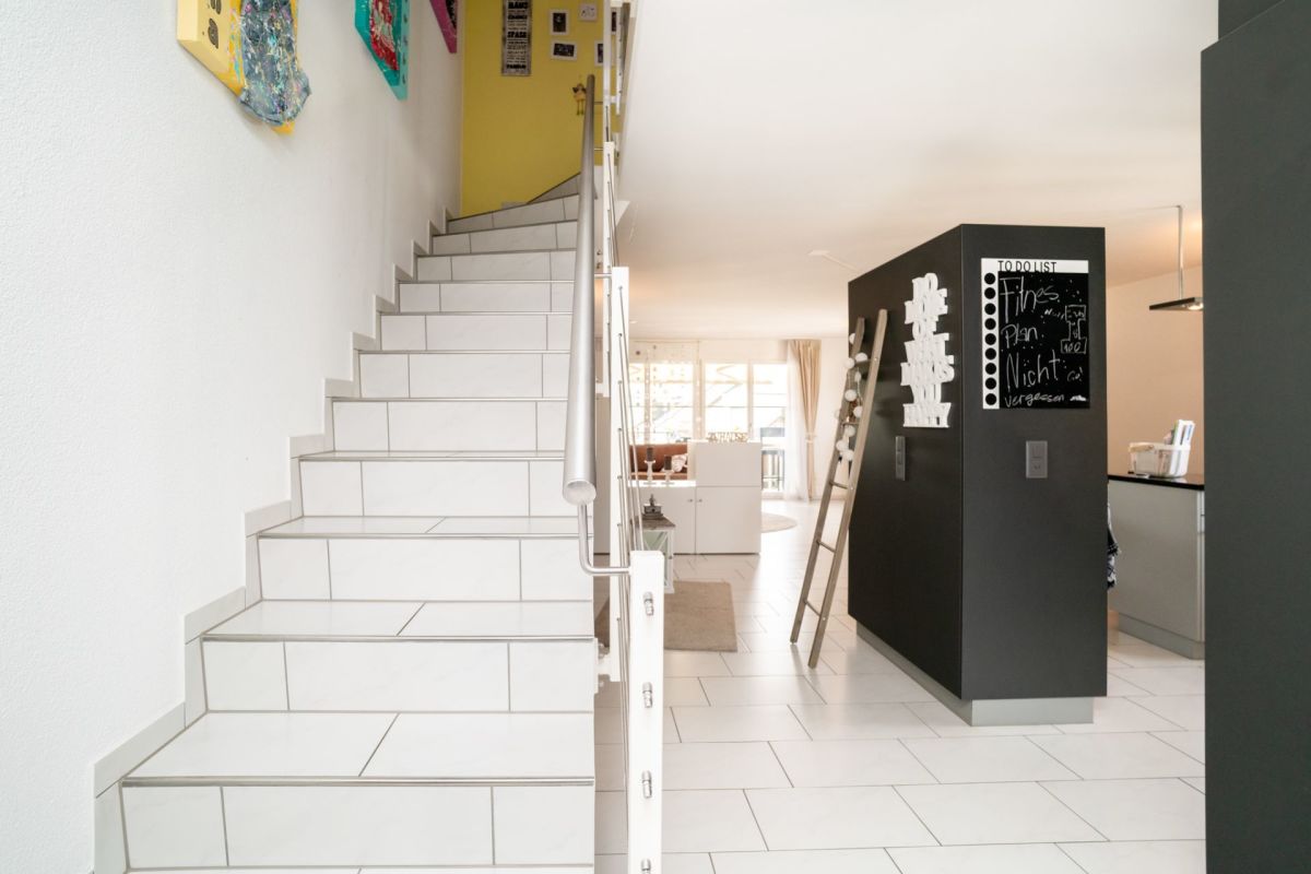 Heller Eingangs- und Treppenbereich mit offenem Blick ins Wohn- und Esszimmer