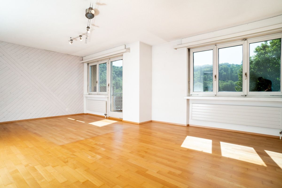 Heller leerer Wohnraum mit Balkon- bzw. Terrassentür und großen Fenstern
