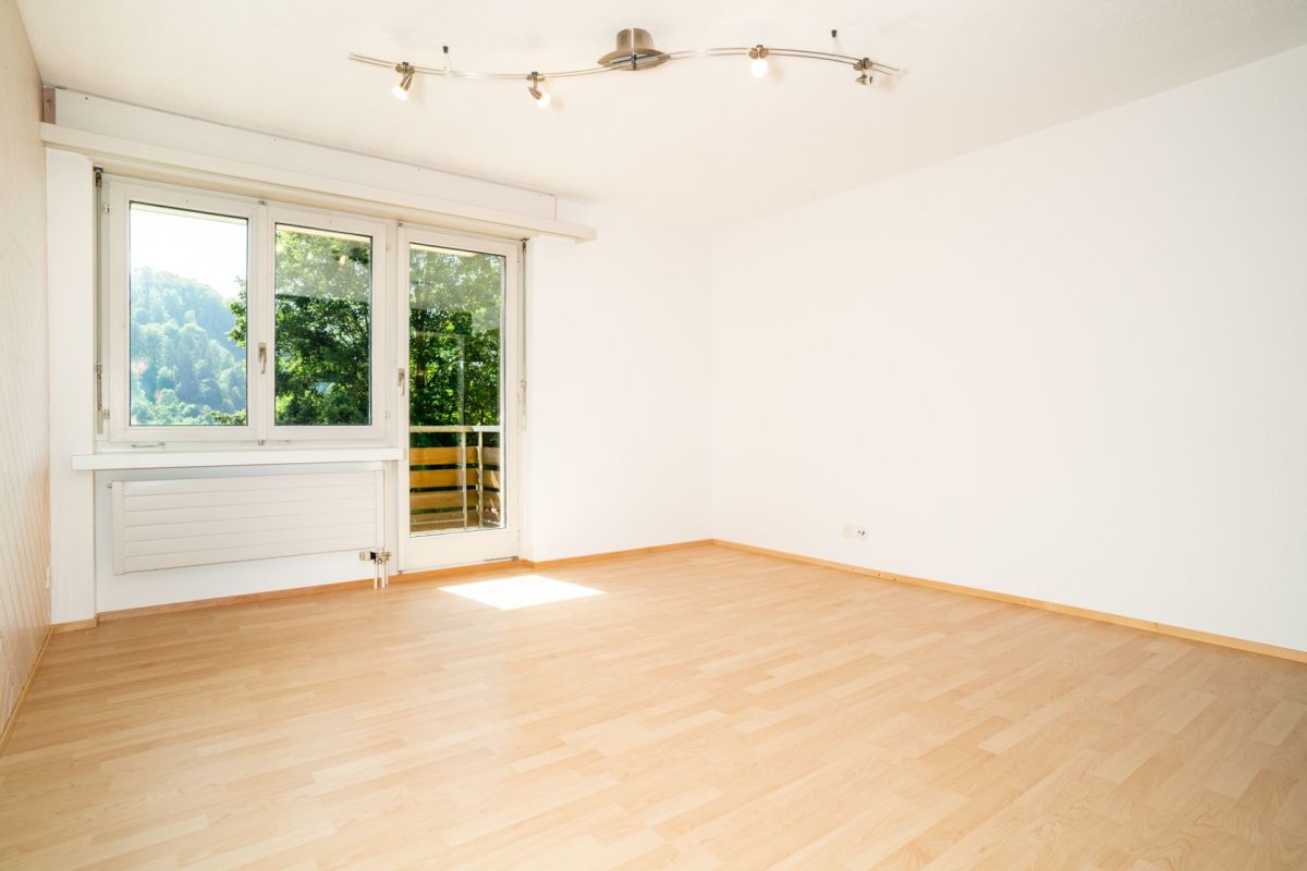 Heller leerer Wohnraum mit Balkon und Blick ins Grüne