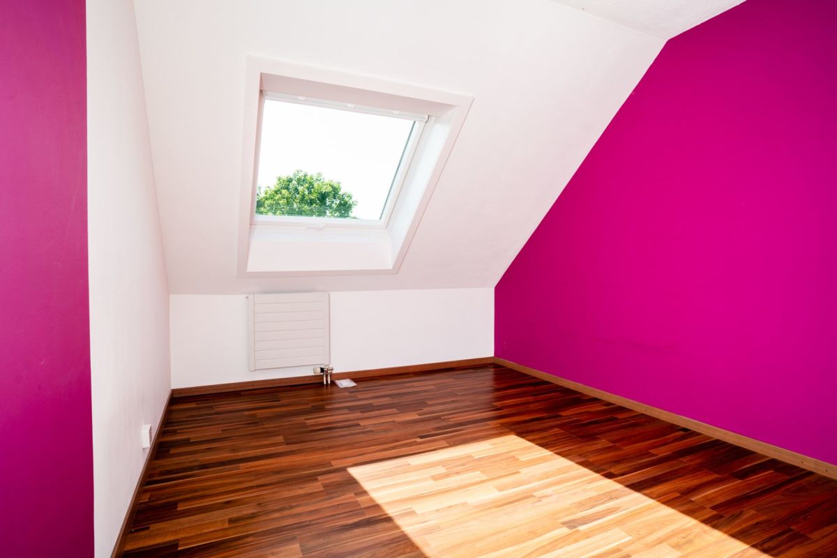 Dachzimmer mit Dachfenster und kräftig farbiger Akzentwand
