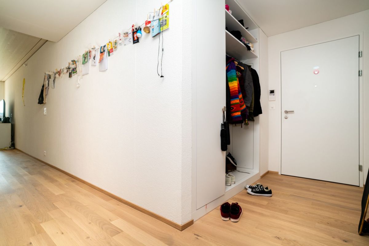 Heller Eingangsbereich mit Garderobe und weißer Haustür