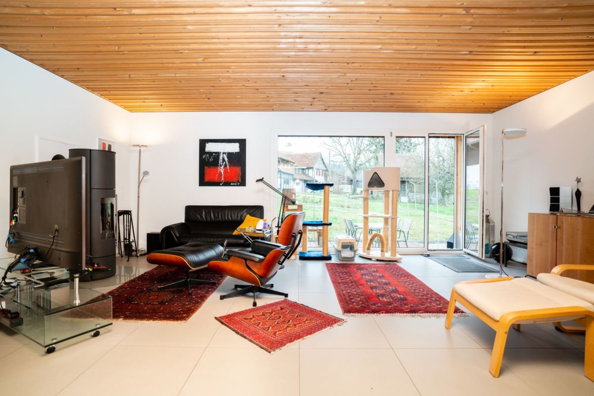 Modernes Wohnzimmer mit Holzbalkendecke und Gartenblick