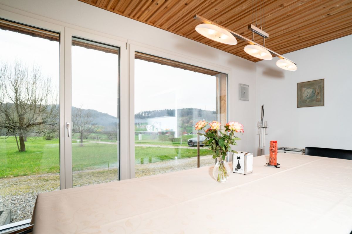Essbereich mit Panoramafenstern und Holzdecke