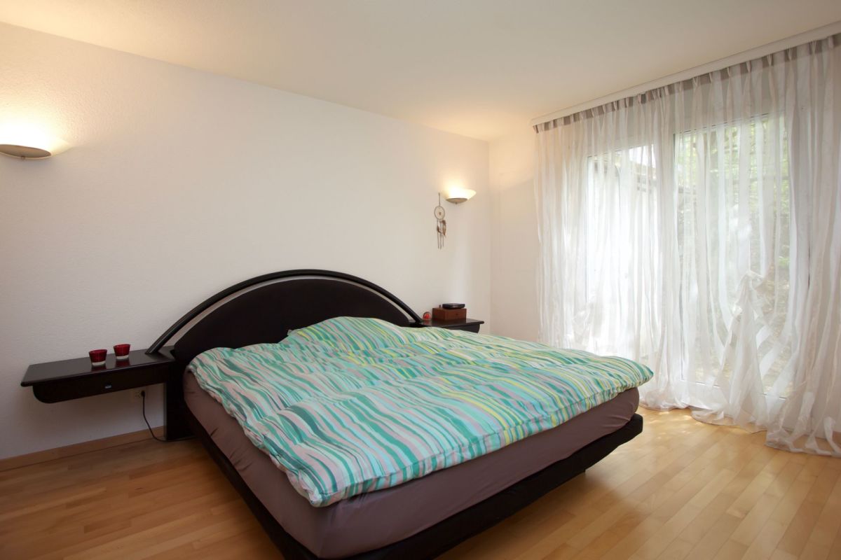 Schlafzimmer mit großem Bett und hellem Tageslicht