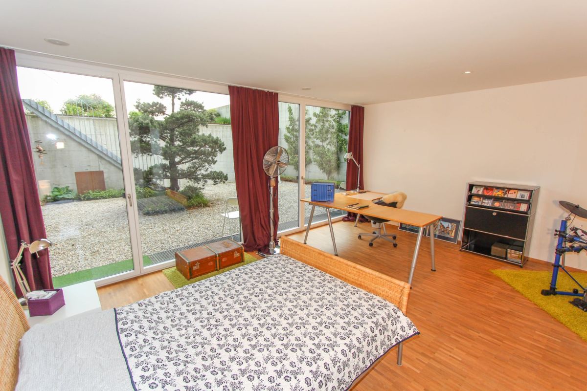 Helles Schlafzimmer mit bodentiefen Fenstern und Arbeitsbereich