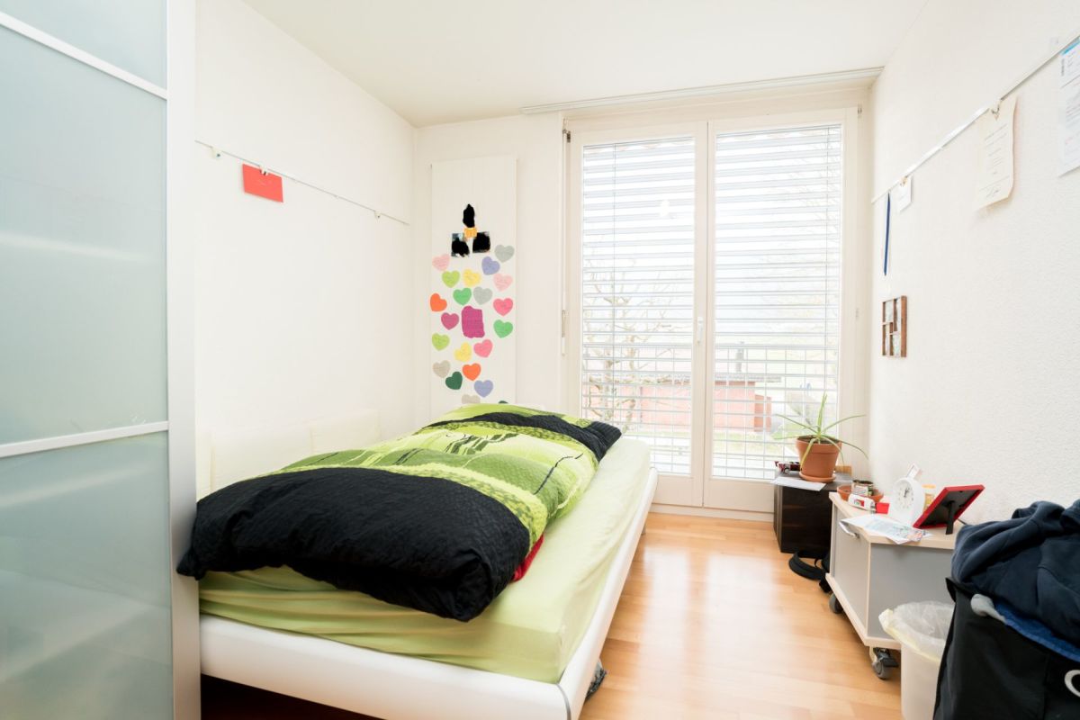 Hell belichtetes Kinder-/Jugendzimmer mit Bett und Balkonfenster
