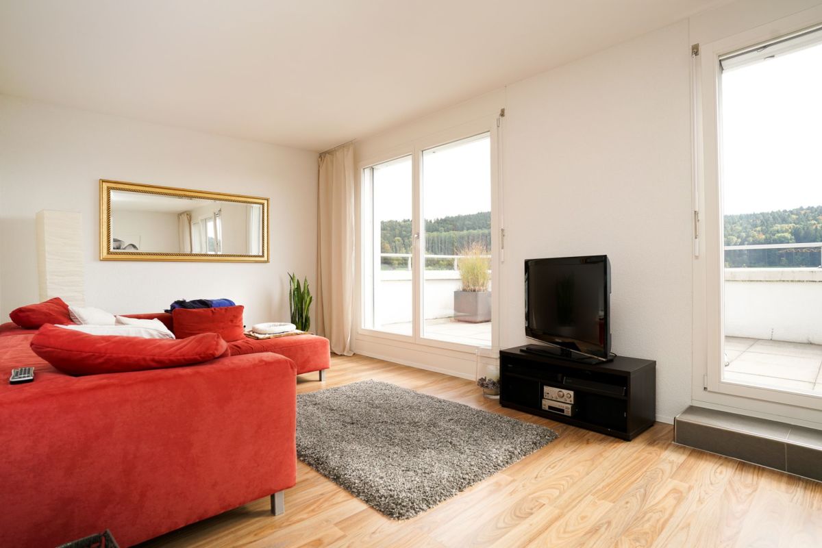 Helles Wohnzimmer mit rotem Sofa und Balkonblick
