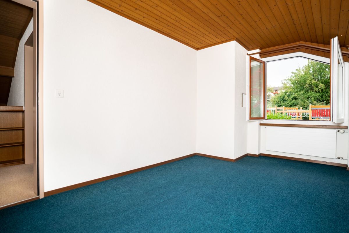 Leeres Zimmer mit Holzdecke und Fensterblick ins Grüne