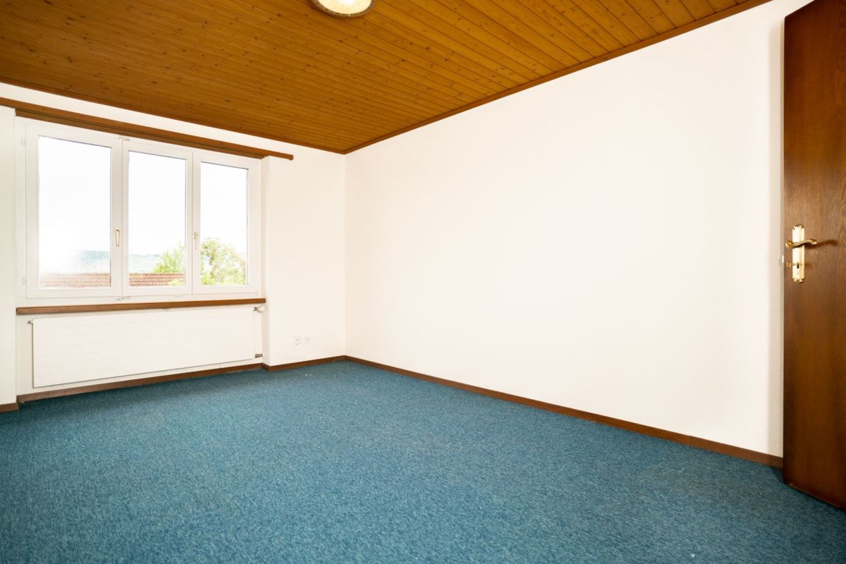 Leerer Raum mit Teppichboden und Holzdecke